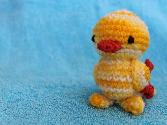 Small crocheted chick on blue background