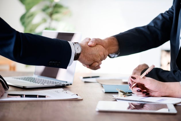 Two men shaking hands across a desk