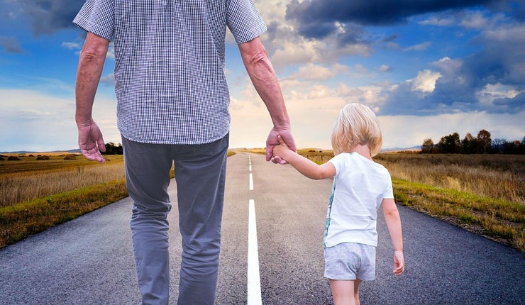 Father holding his child's hand while walking down a road