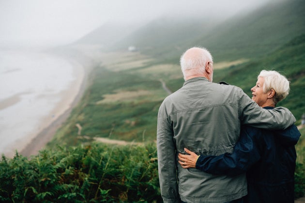 Older couple holding each other while overlooking a valley.