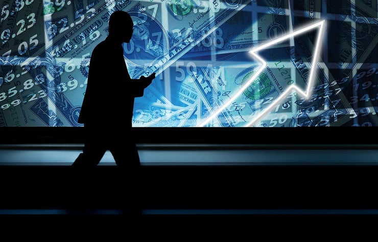Man blacked-out in the forefront with a blue image of financials in background