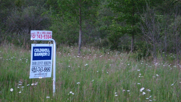 Land with a "For Sale" sign in front of it